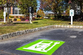 A green and white electric vehicle charging station sign on a street.